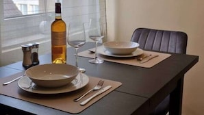 A dining area with a table set for two, a bottle of olive oil, and a painting on the wall. - Casa Mateo - Mediterranean vacation apartment in Bielefeld (Bielefeld)