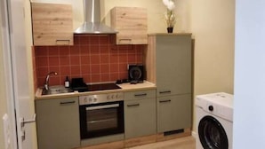 A compact kitchen with a stove, oven, sink, and a washing machine. - Casa Mateo - Mediterranean vacation apartment in Bielefeld (Bielefeld)