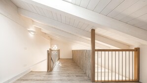 A spacious, high-ceilinged hallway with wooden flooring and a view to an upper level. - Locanda L'orangerie (Crespellano)