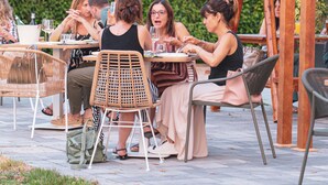 A group of people dining outdoors at a wooden pergola with tables and chairs. - Locanda L'orangerie (Crespellano)