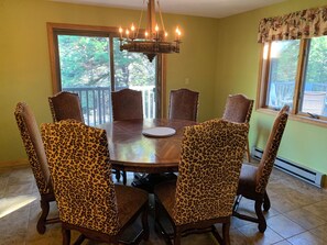 Ein Esszimmer mit einem runden Tisch, sechs Stühlen mit Leopardenmuster und einer Kronleuchter.