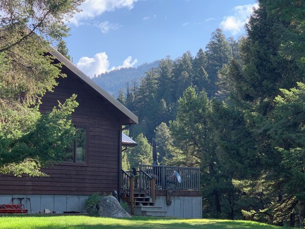 Eine Holzhütte mit Balkon, umgeben von dichtem Wald und Bergen.