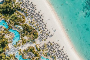 På stranden, hvit sand, strandtelt (mot et tillegg) og solsenger