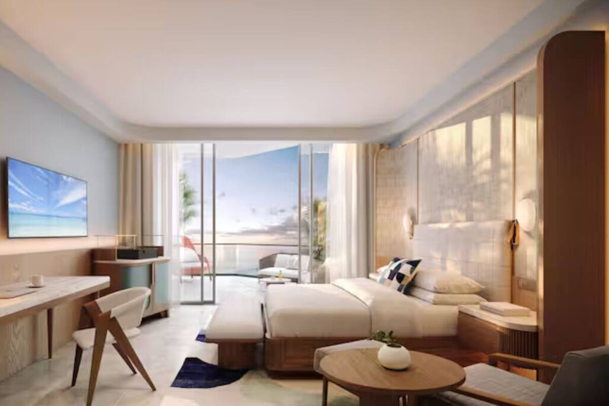 Ein modernes Hotelzimmer mit großem Fenster, einer Couch, einem Schreibtisch und einem kleinen Tisch.