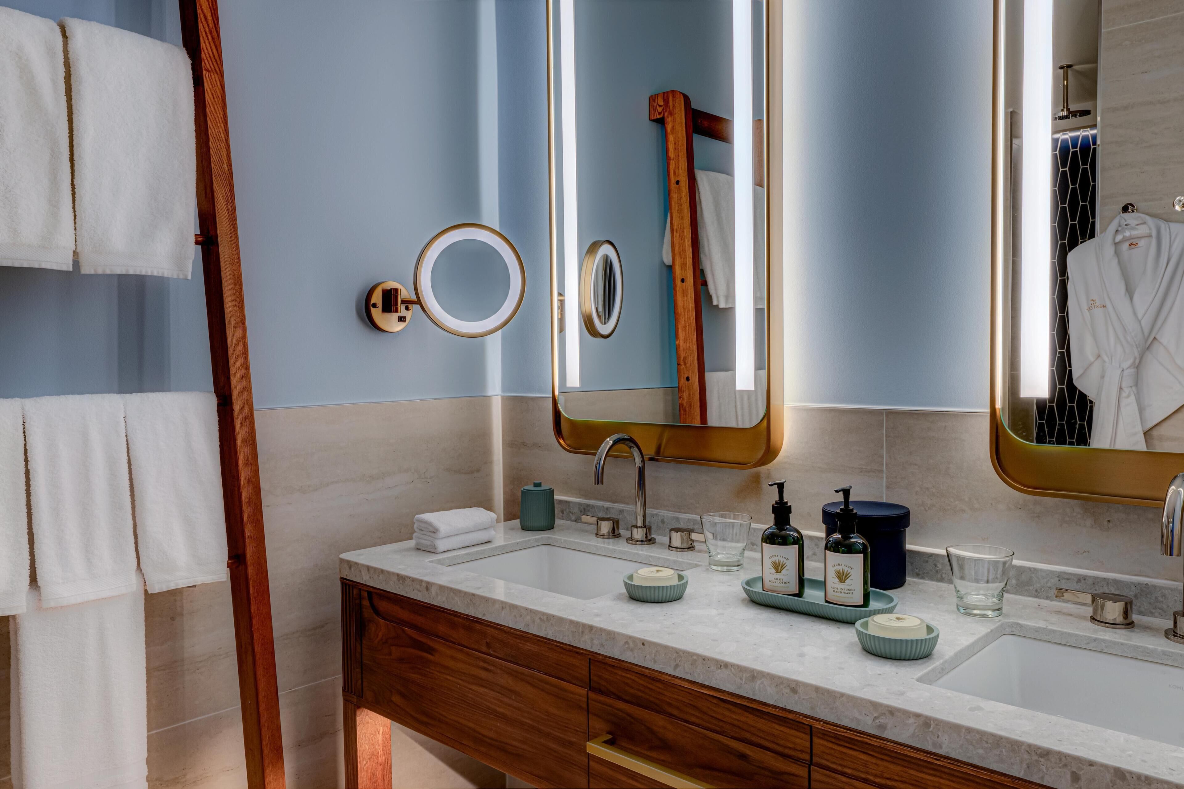 Un baño con tocador doble, un espejo grande y un perchero para toallas.