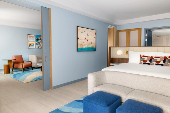 Una habitación de hotel con una cama, un escritorio, una silla y obras de arte en la pared.