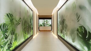 A hallway with a view of a reception desk and a window with a view of greenery.