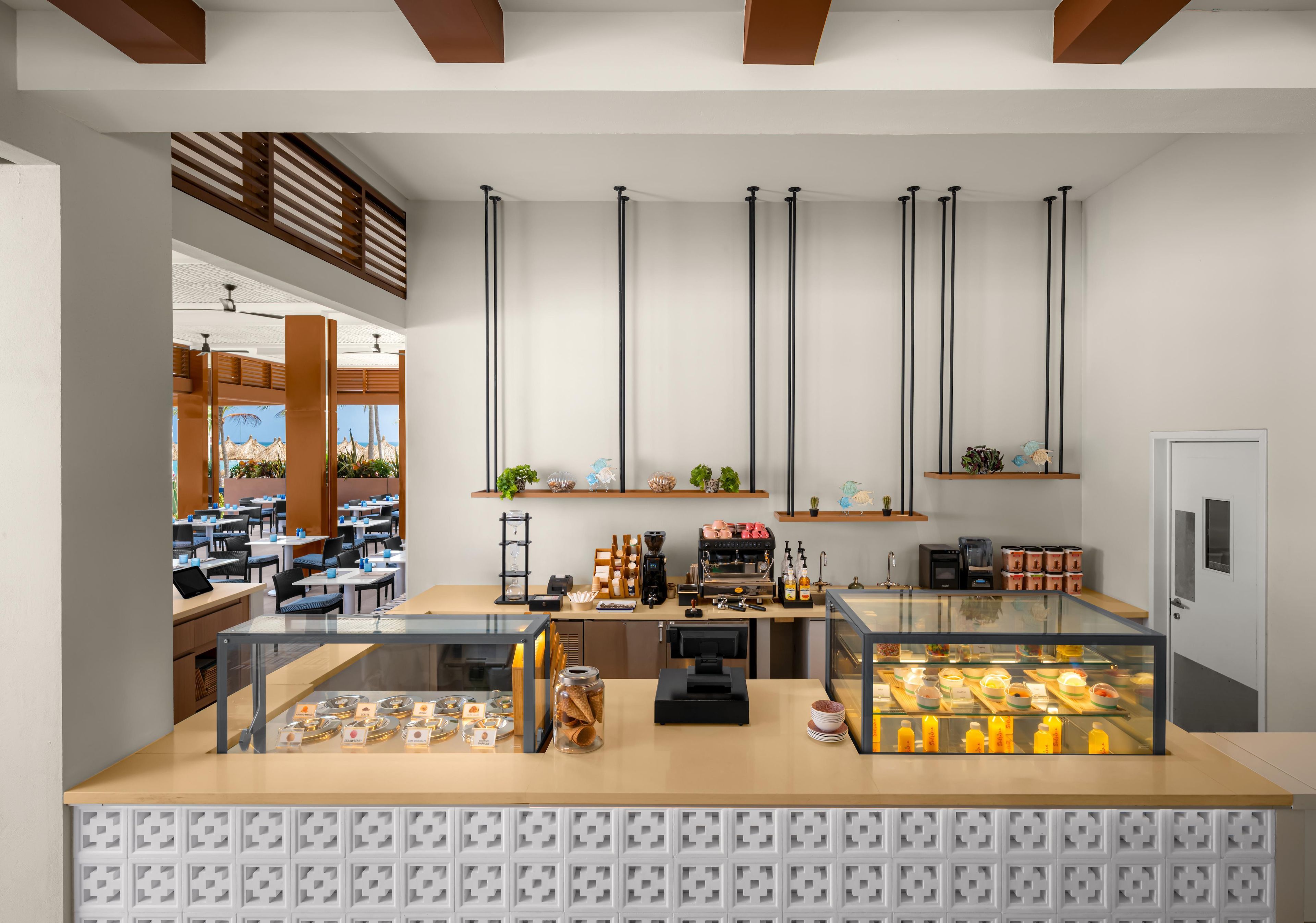 Una cafetería moderna con mostrador, zona de estar y vistas al exterior.
