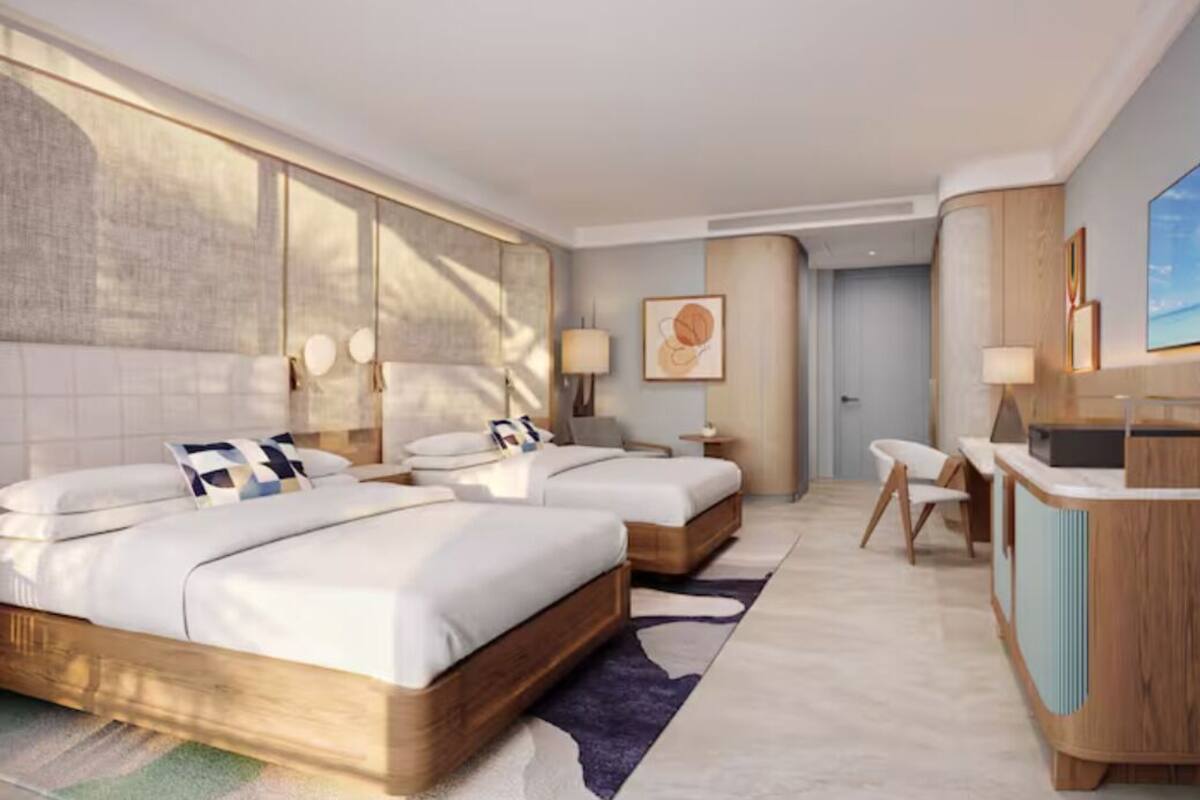 Ein modernes Hotelzimmer mit einem großen Bett, einem Schreibtisch und Blick auf die Stadt.