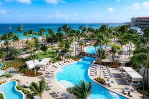 Un resort con una piscina grande, palmeras y vista al océano.