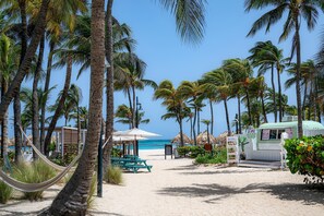 Une plage bordée de palmiers, un hamac, un parasol et un camion-restaurant.