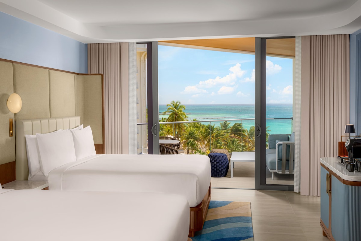 Quarto de hotel com uma cama grande, uma escrivaninha e vista para o oceano.