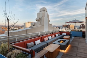 Una terraza en la azotea con un sofá largo, un hogar y vistas panorámicas de la ciudad.