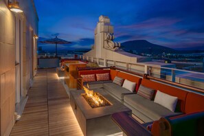 Terraza en la azotea con una chimenea, asientos al aire libre y vistas de la ciudad.