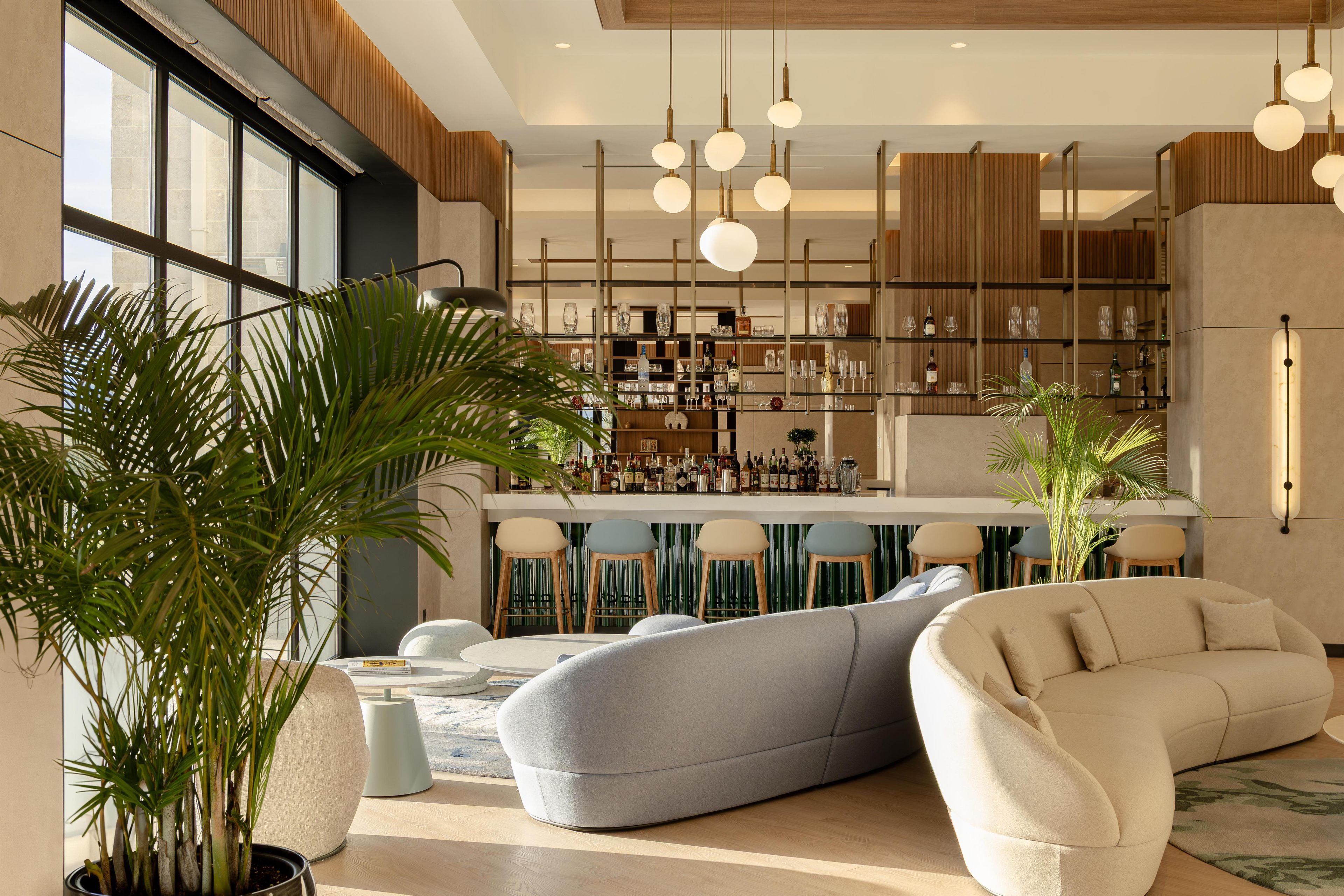 Et moderne interiør med barområde, siddepladser og store vinduer.