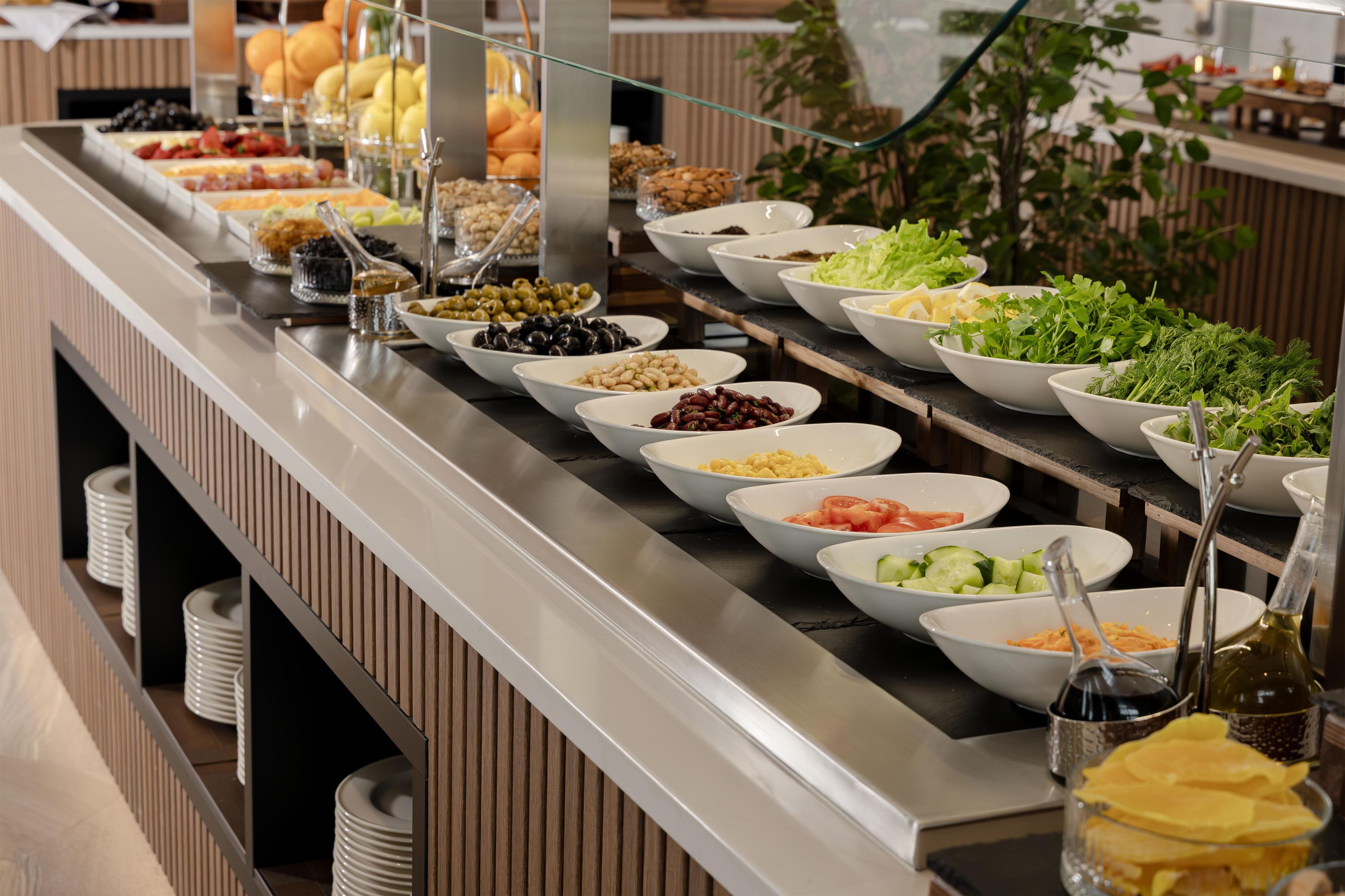 A buffet with various food items including fruits, vegetables, and salads.