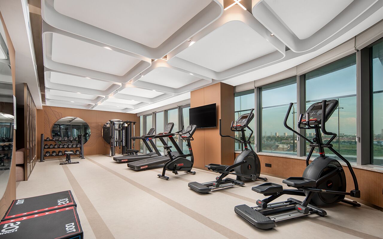 A modern gym with treadmills, elliptical machines, and weight equipment.