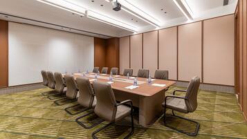 Un salón de conferencias con una larga mesa, varias sillas y botellas de agua.