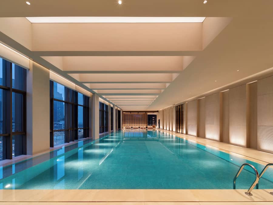 Una piscina interna moderna con un ampio corridoio vista, grandi finestre e un lucernario.
