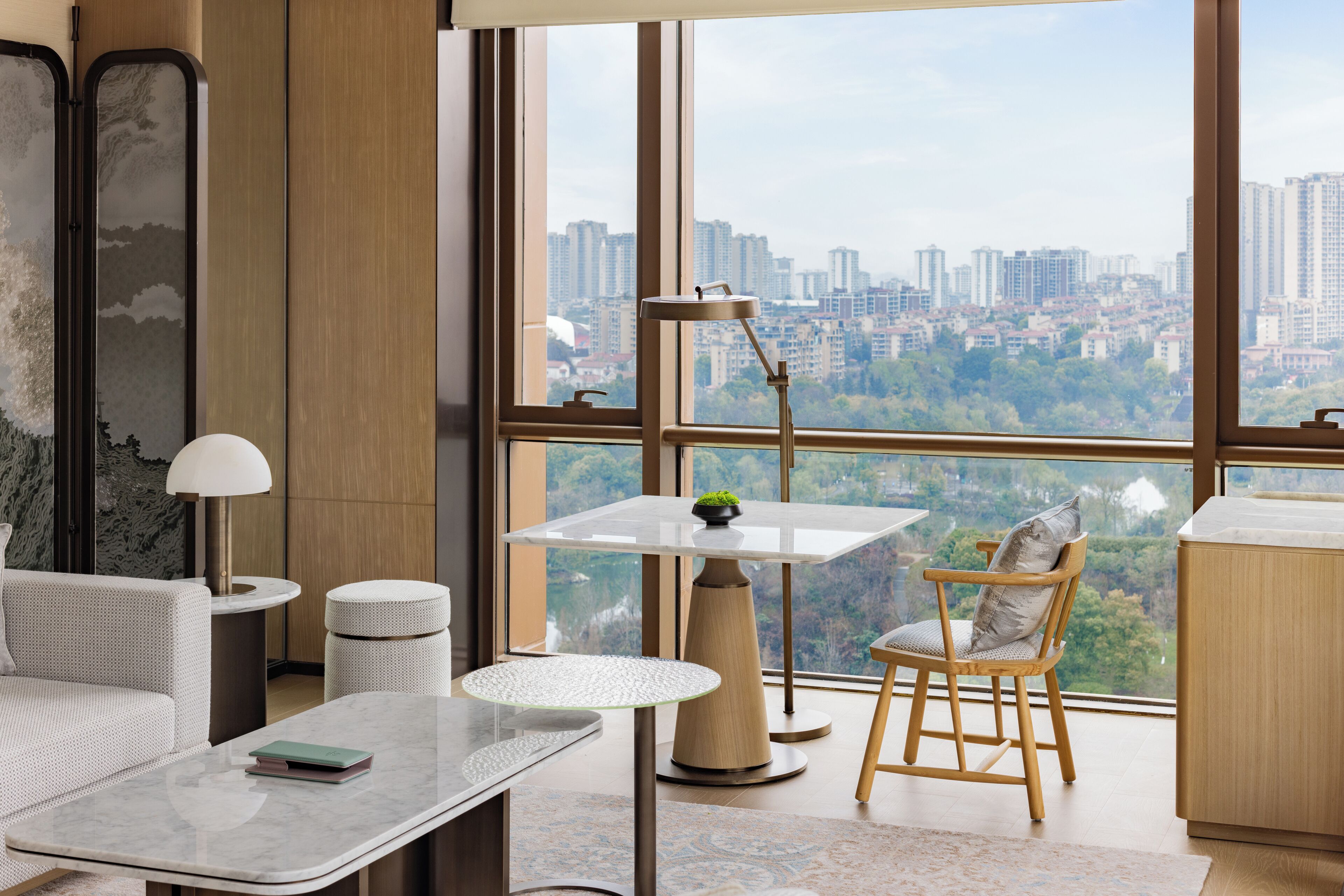 A modern living room with a city view, a round table, a sofa, and a lamp.