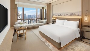 A modern hotel room with a large bed, a dining area, a TV, and a city view. - Doubletree By Hilton Zigong (Zigong)