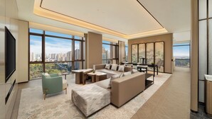 A modern living room with a large TV, comfortable seating, a coffee table, and a view of a cityscape through large windows. - Doubletree By Hilton Zigong (Zigong)