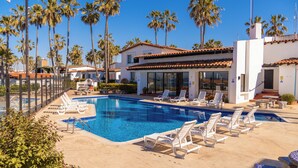 A pool area with lounge chairs and a building with a tiled roof. - La Paloma Rosarito (Playas de Rosarito)