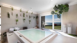 A modern spa room with a large glass-enclosed pool, a view of the sea, and various plants on the walls. - Villa Naaria with Pool (Podstrana)
