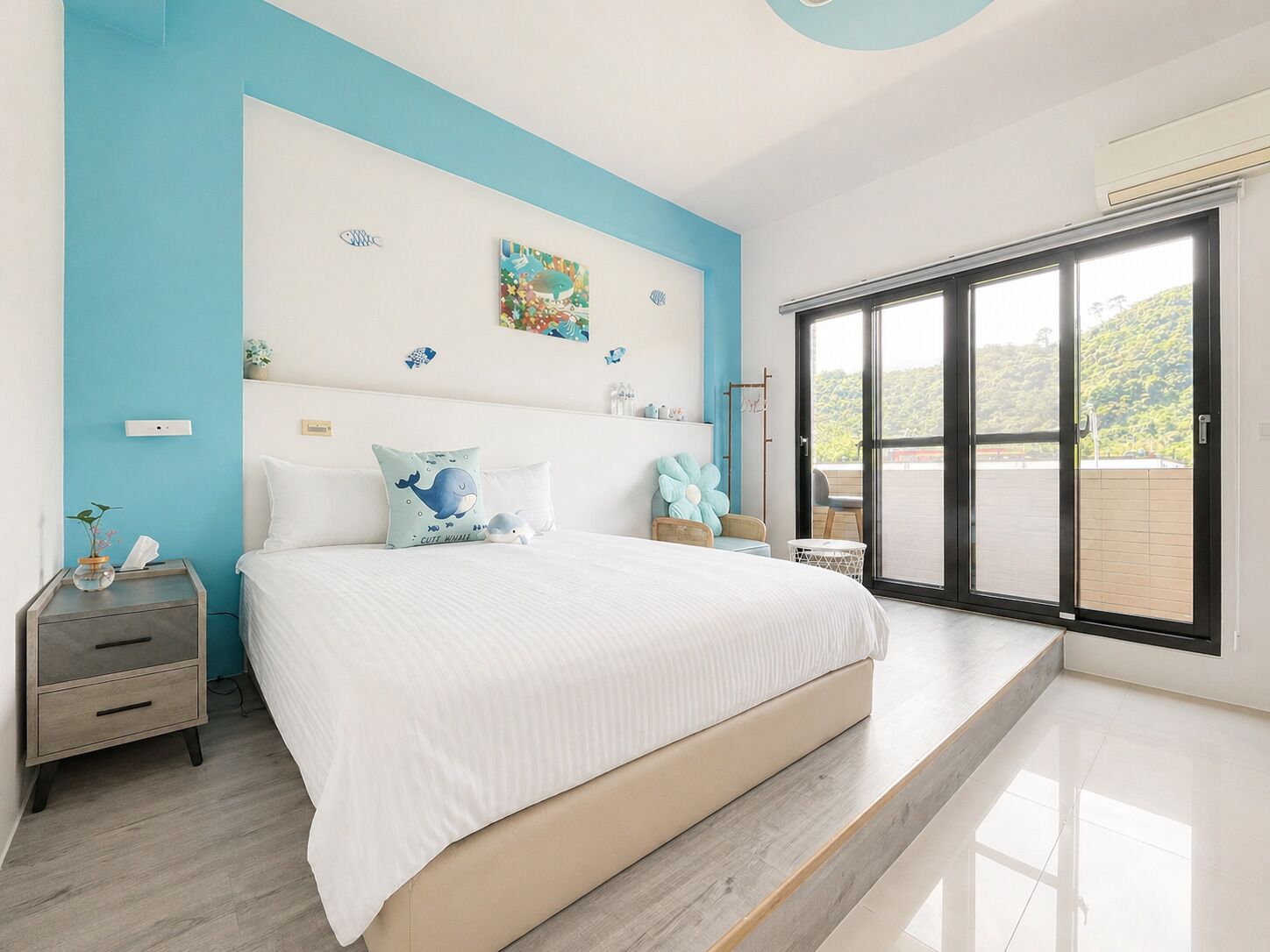 A bedroom with a bed, nightstands, a dresser, a window with a view, and a ceiling with a circular design.