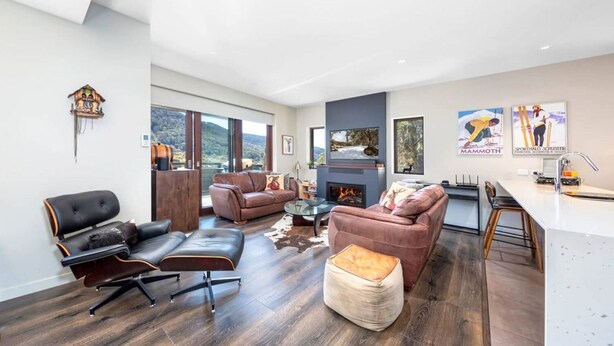 A spacious living area with leather sofas, a fireplace, and a large window offering a mountain view.