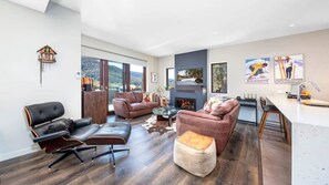 Un salon moderne avec des canapés en cuir, une cheminée et une grande fenêtre donnant sur un paysage montagneux.