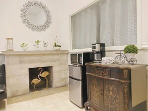 A kitchen with a fireplace, a refrigerator, a microwave, and a coffee maker on the counter.