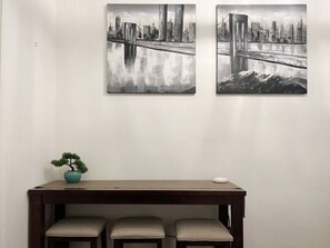A room with a wooden table, two chairs, and two wall-mounted paintings of a bridge.