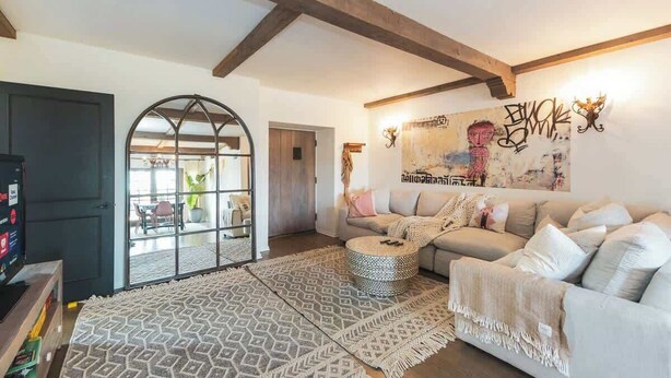 A living room with a sofa, a patterned rug, and a large window. - Luxury Villa w/ Pool, Mountain Views near NASA (Altadena)
