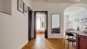 Un interior moderno con suelo de madera, una zona de comedor con mesa y sillas, y un dormitorio con cama y mesita de noche.