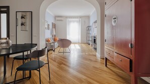 Amplia sala de estar con piso de madera, una mesa de comedor con sillas, un sofá y un armario rojo.