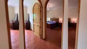 A hallway with a wooden door leading to a bedroom with a bed and a nightstand. - Spacious Villa near the Beach (Saidia)