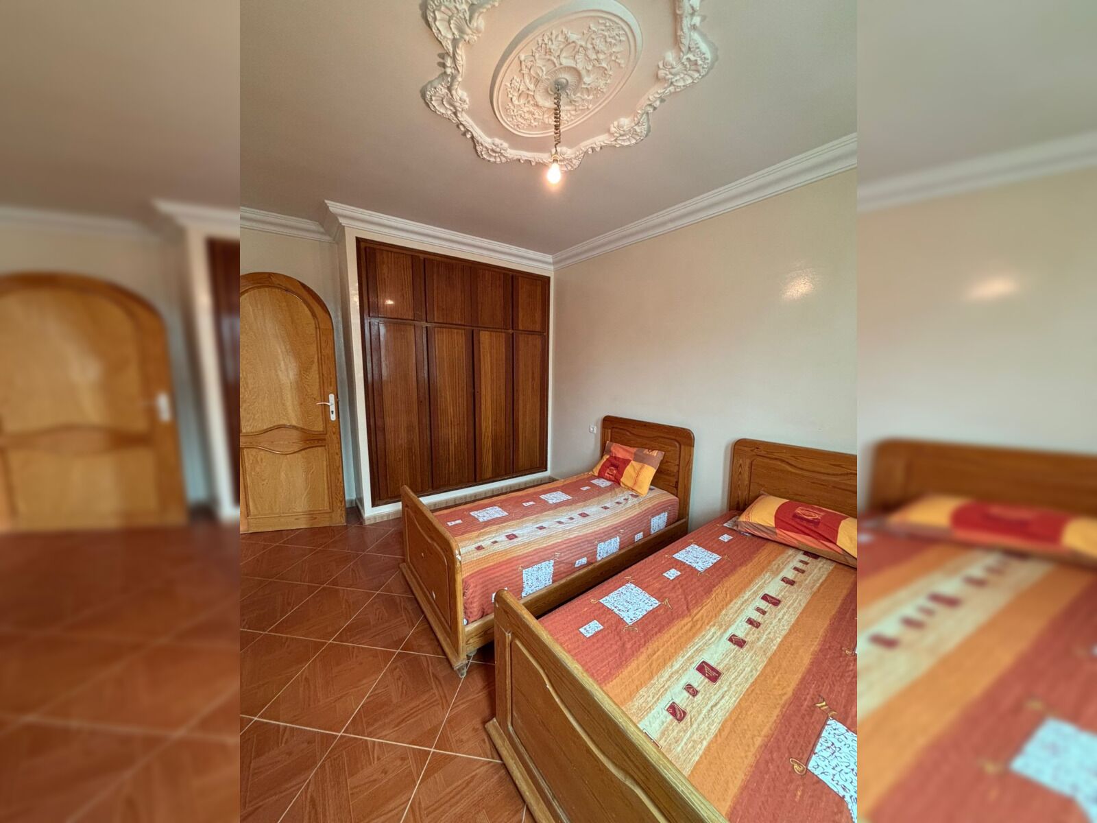 A bedroom with two wooden beds, a wardrobe, and a door.