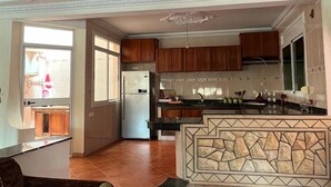 A spacious kitchen with wooden cabinets, a refrigerator, and a tiled backsplash. - Spacious Villa near the Beach (Saidia)