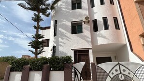 A modern two-story building with a white facade, multiple windows, and a gated entrance. - Spacious Villa near the Beach (Saidia)