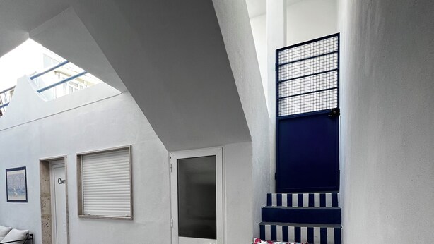 A modern interior with a staircase, a door, and a window with a metal grid.