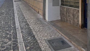 A cobblestone street with buildings on one side.