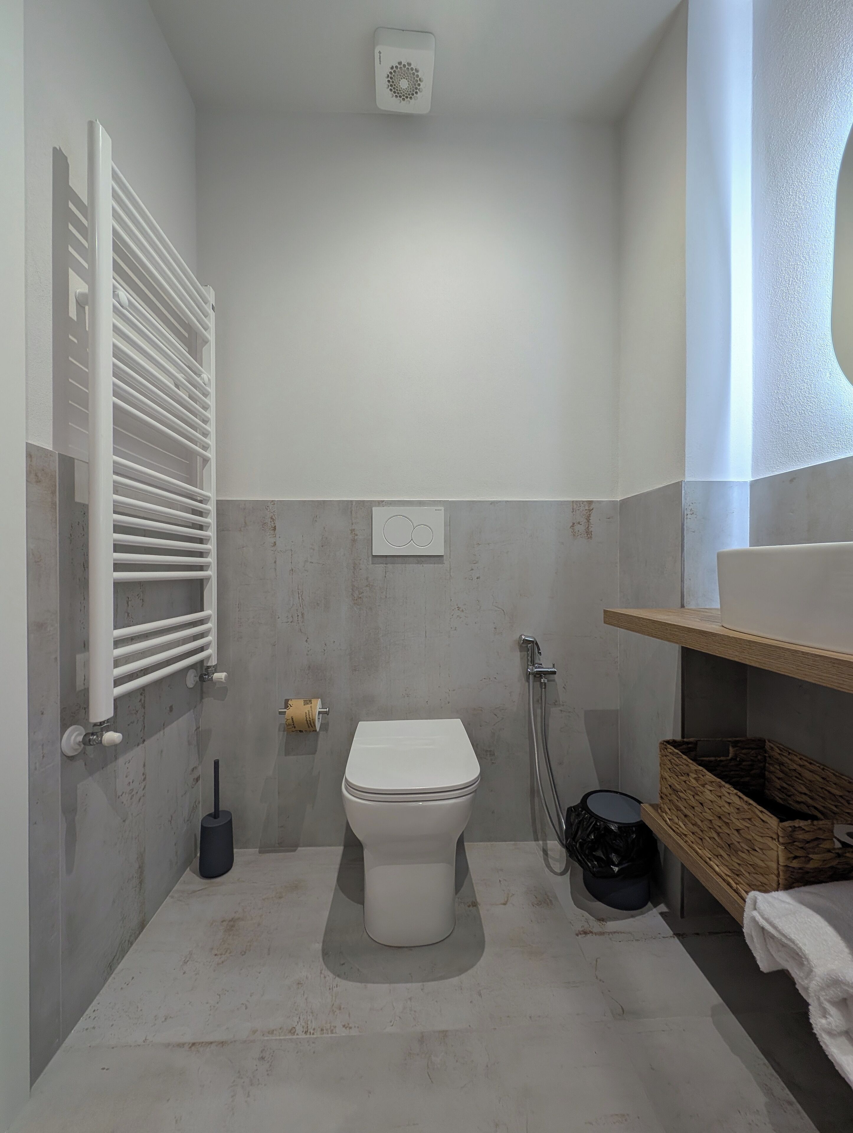 Ein Badezimmer mit Toilette, Dusche, Handtuchhalter und einer kleinen Ablagefläche.