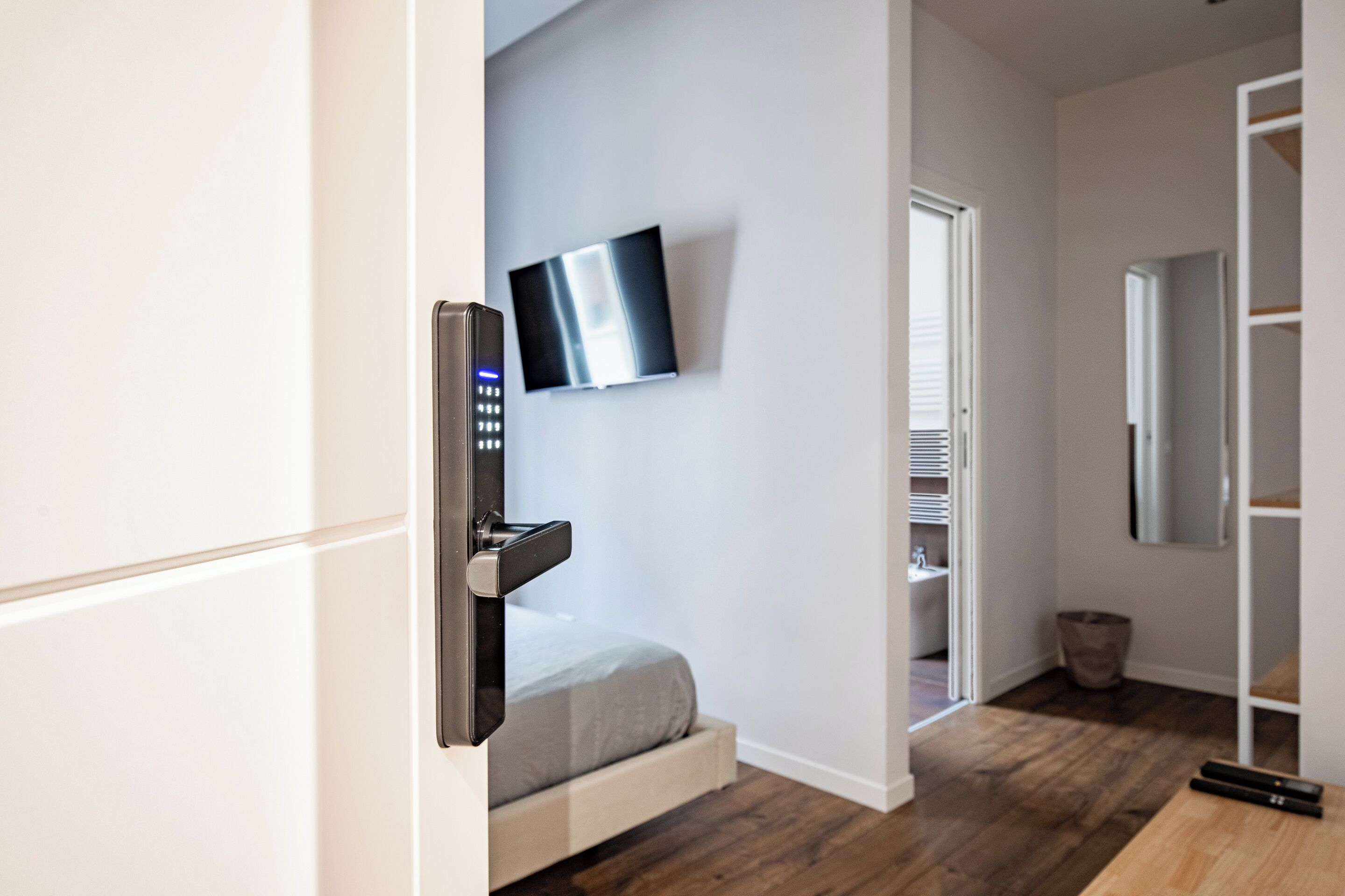Une chambre moderne avec un lit, un téléviseur fixé au mur et un plancher en bois.