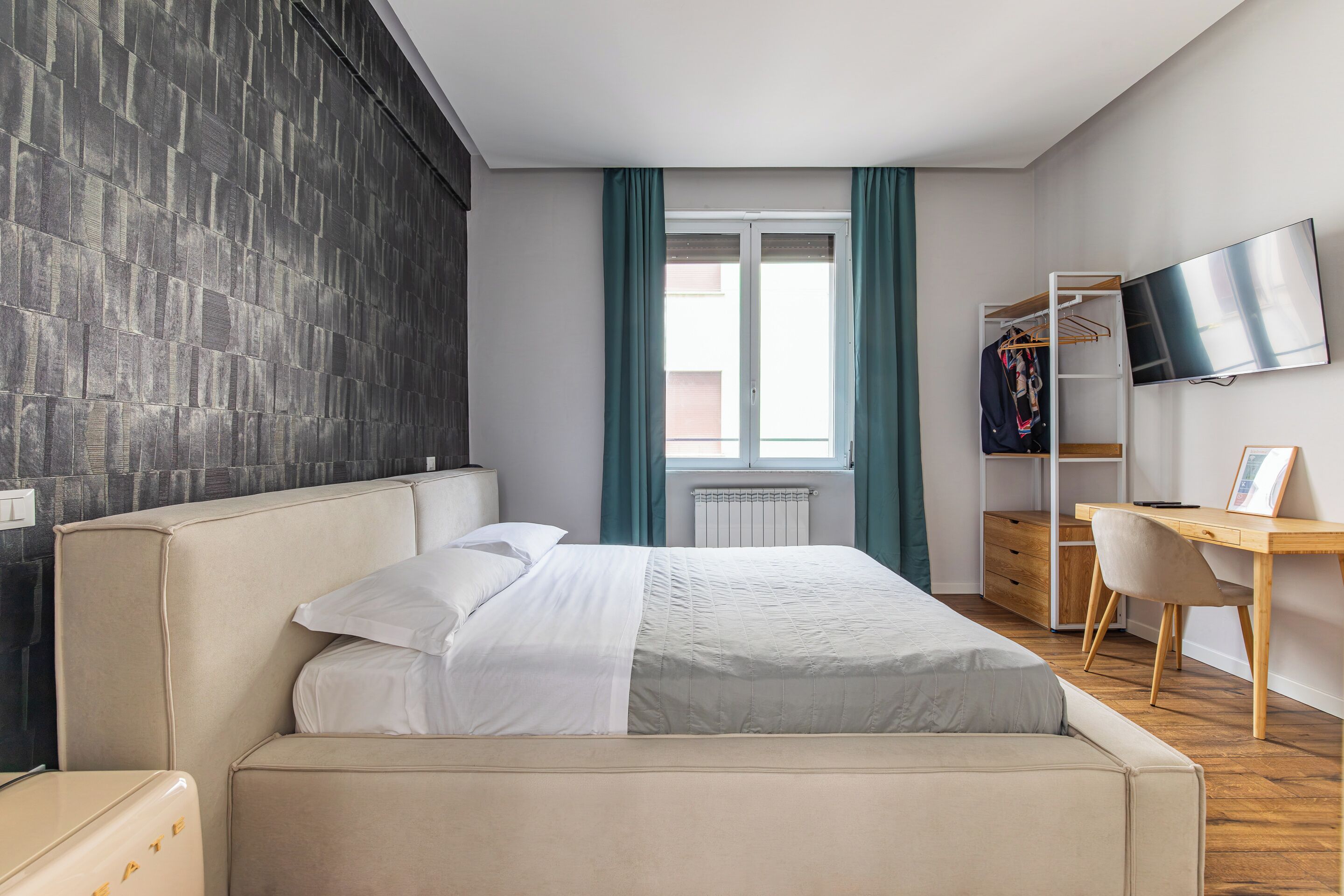 A bedroom with a bed, a desk, a chair, a TV, and a wardrobe.