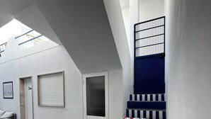 A modern interior with a staircase, a door, and a window with a metal grid.