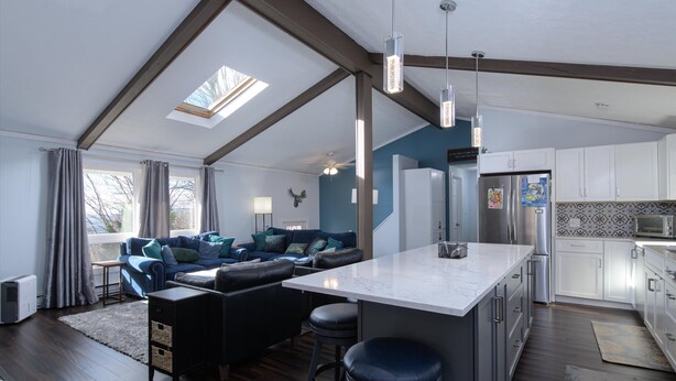 A spacious living area with a large sofa, a kitchen with white cabinets, and a skylight. - Mountain side, remodeled  4 br neat trail head. (Wilmington)