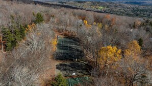 A tennis court surrounded by trees with autumn foliage, set in a hilly landscape. - Mountain side, remodeled  4 br neat trail head. (Wilmington)