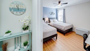 A bedroom with two beds, a ceiling fan, a bedside table with a lamp, and a decorative clock on the wall. - Tremendous space with covered patio in central McKinney (McKinney)