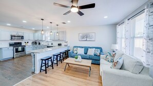 A modern kitchen with a central island, bar stools, a dining table, and a sofa in a living area. - Tremendous space with covered patio in central McKinney (McKinney)